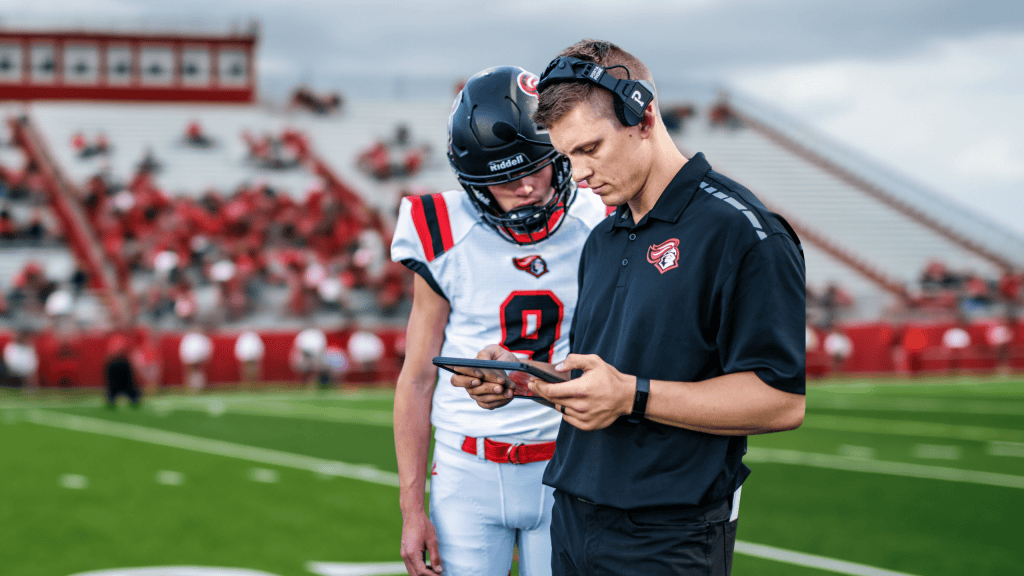 coach and football player on the field looking at the iPad