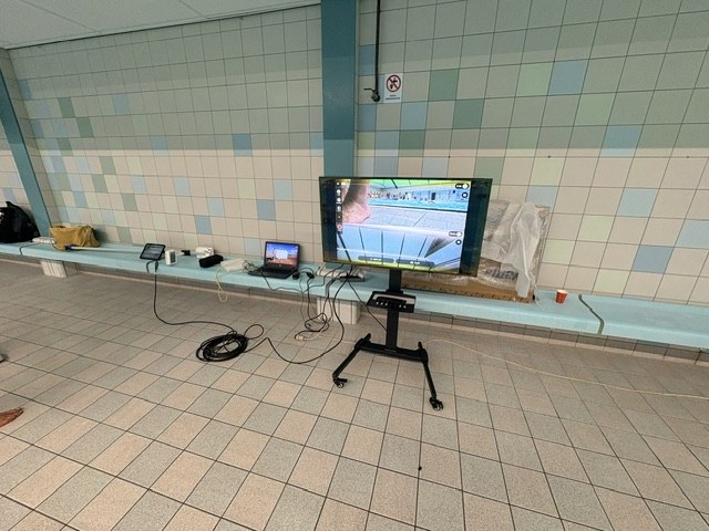 Poolside television on a rolling stand showing the delayed underwater footage, with the iPad connected by HDMI